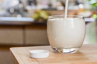 El yağan taze kefir probiotik suya beyaz şişe açık cam mutfak masasında