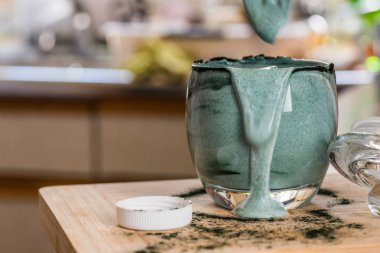 Mutfak masasının üzerinde yeşil spirulina tozu ile portre görünümü taze kefir probiotik içki açık cam içinde karışık
