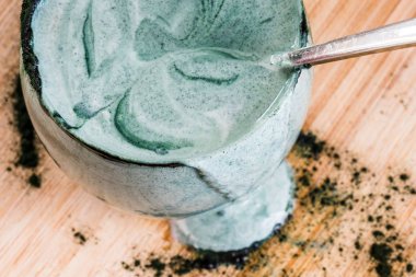 Mutfak masasının üzerinde yeşil spirulina tozu ile portre görünümü taze kefir probiotik içki açık cam içinde karışık