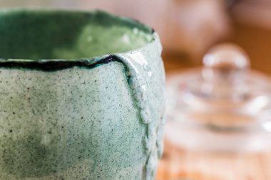 Closeup görünümü cam mutfak masasının üzerinde ahşap tahta üzerinde yeşil spirulina tozu ile karışık taze kefir probiotik içeceği boşalttı