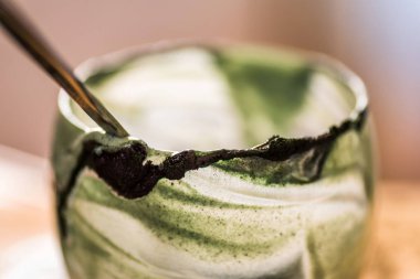 Closeup görünümü cam mutfak masasında içinde kaşık ile yeşil spirulina mamasının taze kefir probiotik içeceği boşalttı