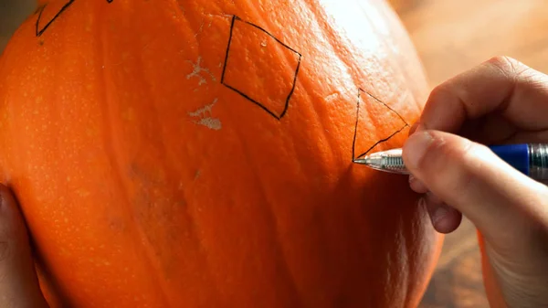 Young boy carving and painting a pumpkin for Halloween on a table — Stock Photo, Image