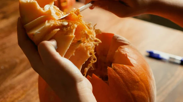 Young boy carving and painting a pumpkin for Halloween on a table — Stock Photo, Image