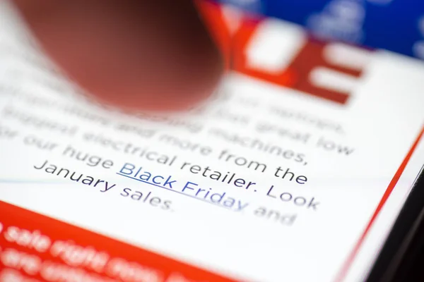 Human finger thumb over Black Friday Sale text link on shopping app on smartphone screen closeup