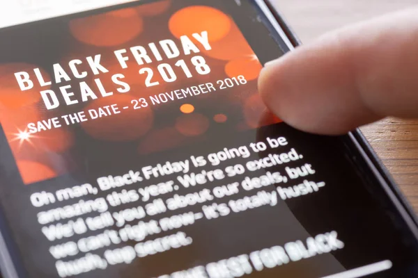 Human finger thumb over Black Friday Deals 2018 text on shopping app on smartphone screen closeup