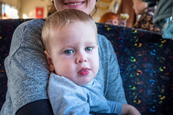 Closeup portret van de jonge blonde baby kijken naar smartphone zitten met moeder terwijl het reizen per bus — Stockfoto