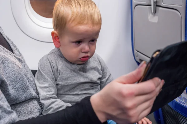 Retrato de primer plano del bebé rubio joven viendo la tableta sentada con la madre mientras viaja avión — Foto de Stock