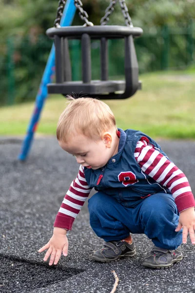 Ciekaw chłopca po raz pierwszy dotyka powierzchni placu zabaw — Zdjęcie stockowe