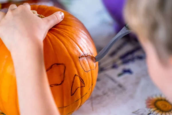 Szőke fiú carving pumpkin jack-o-lantern, késsel — Stock Fotó