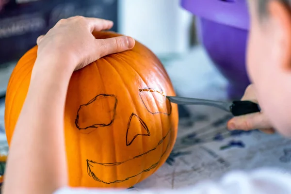 Szőke fiú carving pumpkin jack-o-lantern, késsel — Stock Fotó
