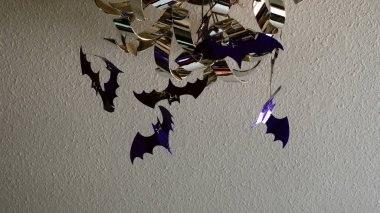 Genç kadın tavan lamba parlak plastik yarasalar koyarak Cadılar Bayramı kutlama için ev dekorasyon