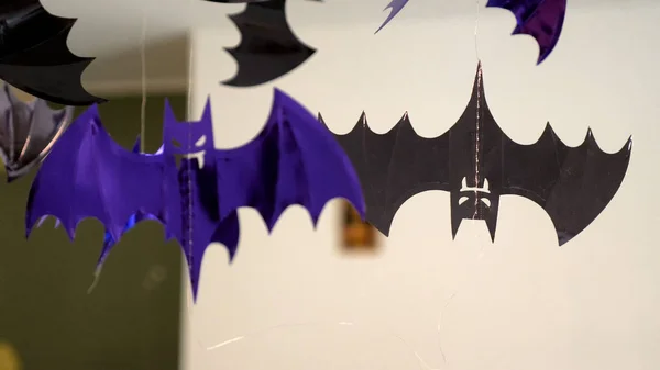 closeup view shiny plastic bat decoration hanging on ceiling lamp for halloween celebration