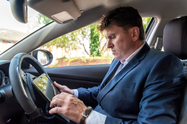 Empresario trabajando en la tableta dentro del coche en el día brillante — Foto de Stock