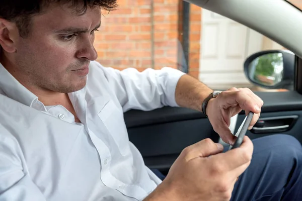 Empresario que trabaja en la tableta y el teléfono inteligente dentro del coche en el día brillante — Foto de Stock