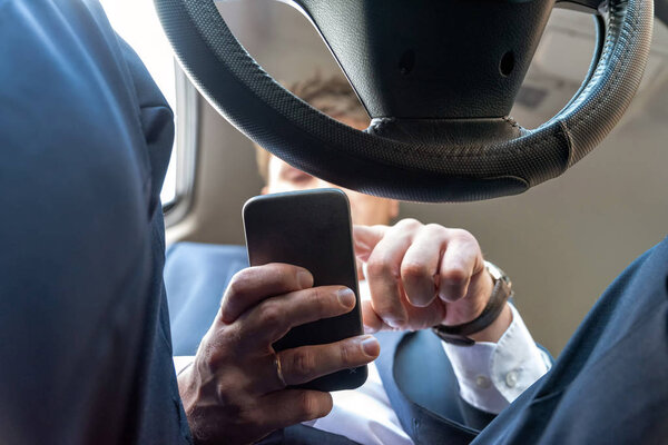 Businessman working on tablet and smartphone inside car on bright day