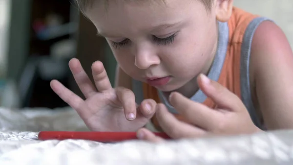 Kind jongen kijken smartphone spelen op bed thuis. afstandsonderwijs; — Stockfoto