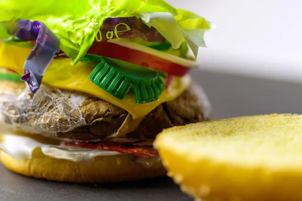 Burger filled with plastic waste and paper cardboard. Recycled waste in our food concept.