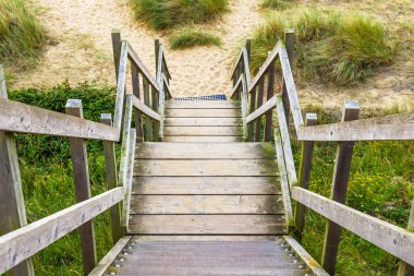 Sahile doğru inen ahşap merdivenler ve Lowestoft Suffolk 'taki kum tepeleri.