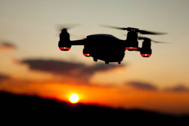 Günbatımında gökyüzünde bir dron. Dışarıdaki kuadrokopteri kapatın..