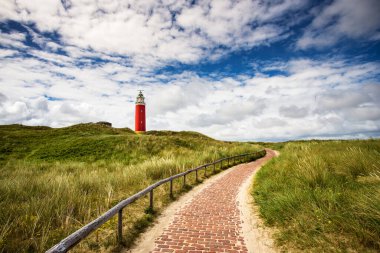 Düz kumlu bir sahilde denizin arka planında duran güzel bir deniz feneri.