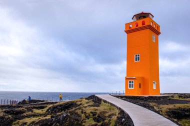Düz kumlu bir sahilde denizin arka planında duran güzel bir deniz feneri.