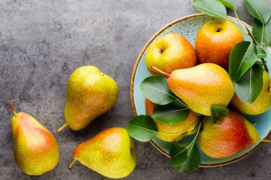 Tabağında yapraklar olan taze bir armut. Gri taş masa.