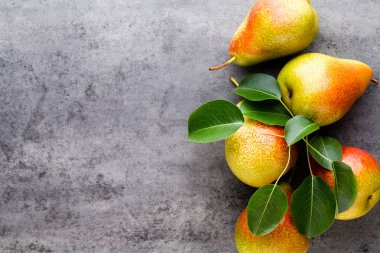Tabağında yapraklar olan taze bir armut. Gri taş masa.