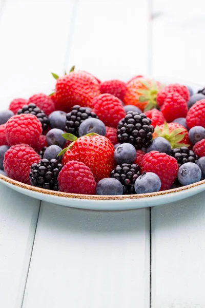 Fresh berry salad on blue dishes. Vintage wooden background. — Stock Photo, Image