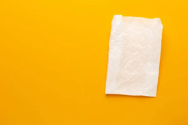 Weiße Papiertüte auf gelbem Hintergrund. — Stockfoto
