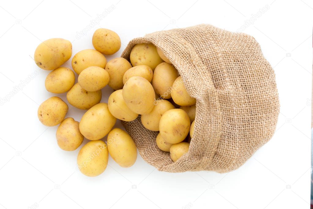 Sack of fresh raw potatoes on wooden background, top view