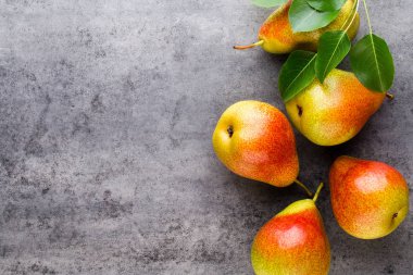 Tabağında yapraklar olan taze bir armut. Gri taş masa.