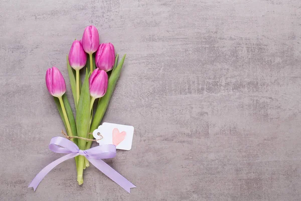 Spring greeting card, pink color tulips on the gray background. — Stock Photo, Image