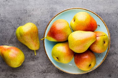 Tabağında yapraklar olan taze bir armut. Gri taş masa.