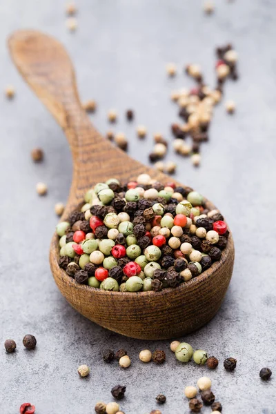 Peperkorenmix in een houten kom op grijze tafel. — Stockfoto