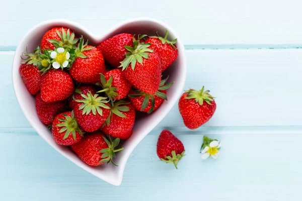 Çilekli kalp. Beyaz ahşap ta tabakta taze çilek