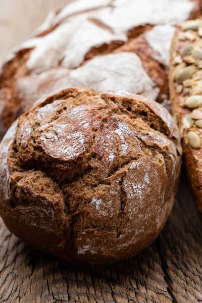 Gold rustikal krustige Brotlaibe und Semmeln auf Holzgrund — Stockfoto