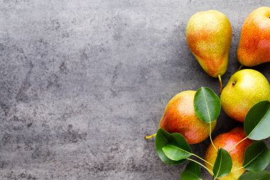 Tabağında yapraklar olan taze bir armut. Gri taş masa.