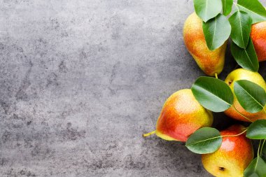 Tabağında yapraklar olan taze bir armut. Gri taş masa.