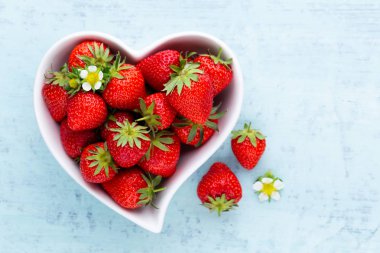 Çilekli kalp. Beyaz ahşap ta tabakta taze çilek