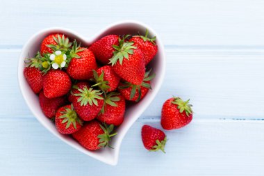 Çilekli kalp. Beyaz ahşap ta tabakta taze çilek