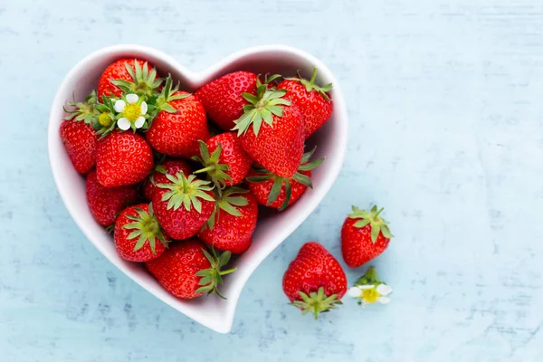 Çilekli kalp. Beyaz ahşap ta tabakta taze çilek
