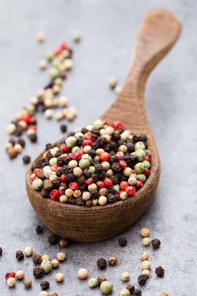 Peperkorenmix in een houten kom op grijze tafel. — Stockfoto