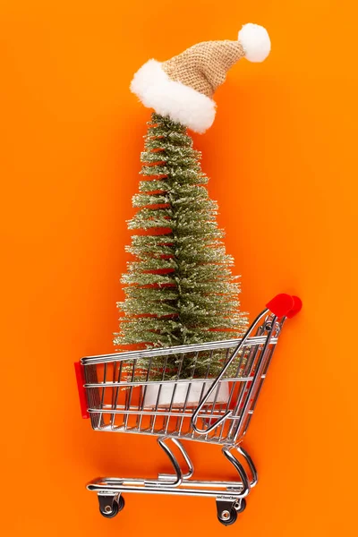 Shopping vagn med julgran på rött bord. — Stockfoto