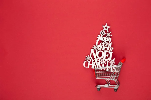 赤いテーブルの上にクリスマスツリーとショッピングカート. — ストック写真