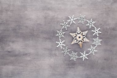 Gri arkaplanda beyaz kar taneleri çelenk süslemeleri. 