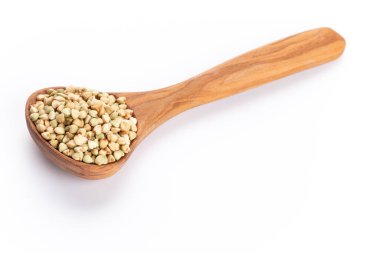 Beyaz arka planda çiğ karabuğday ve tahta kaşık.