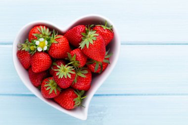 Çilekli kalp. Beyaz ahşap masadaki taze çilekler. Üst görünüm, alanı kopyala. 