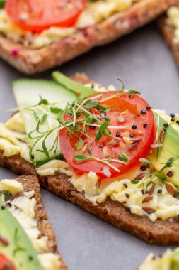 Krem peynirli, sebzeli ve salamlı mini sandviçler. Salatalıklı sandviçler, turp, domates, gri arka planda salam, üst manzara. Düz yatıyordu.
