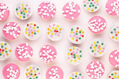 Beyaz arka planda çok renkli, güzel dekore edilmiş muffinler..