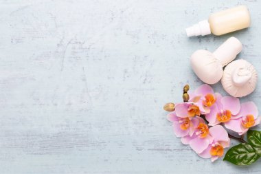 Spa aromaterapi arka planı, basit orkide çiçekleriyle süslenmiş çeşitli güzellik ürünleri..